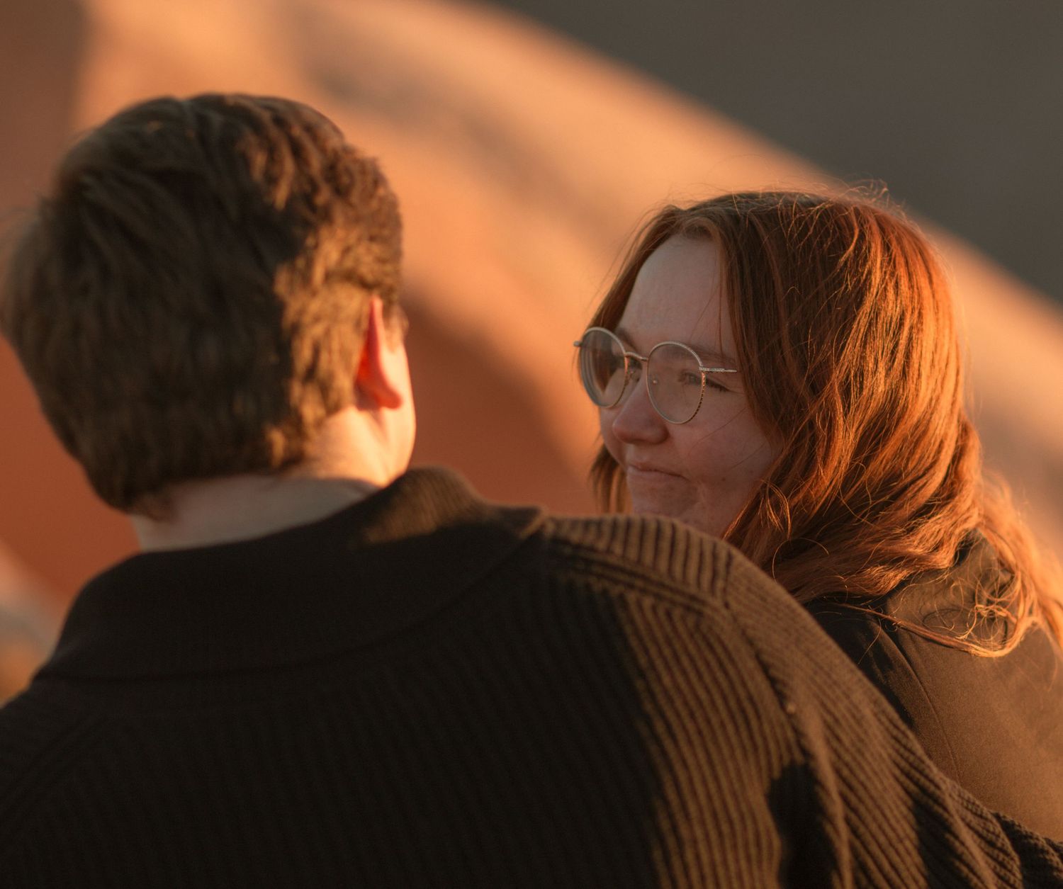 Couple in warm lighting embracing during romantic golden hour moment.