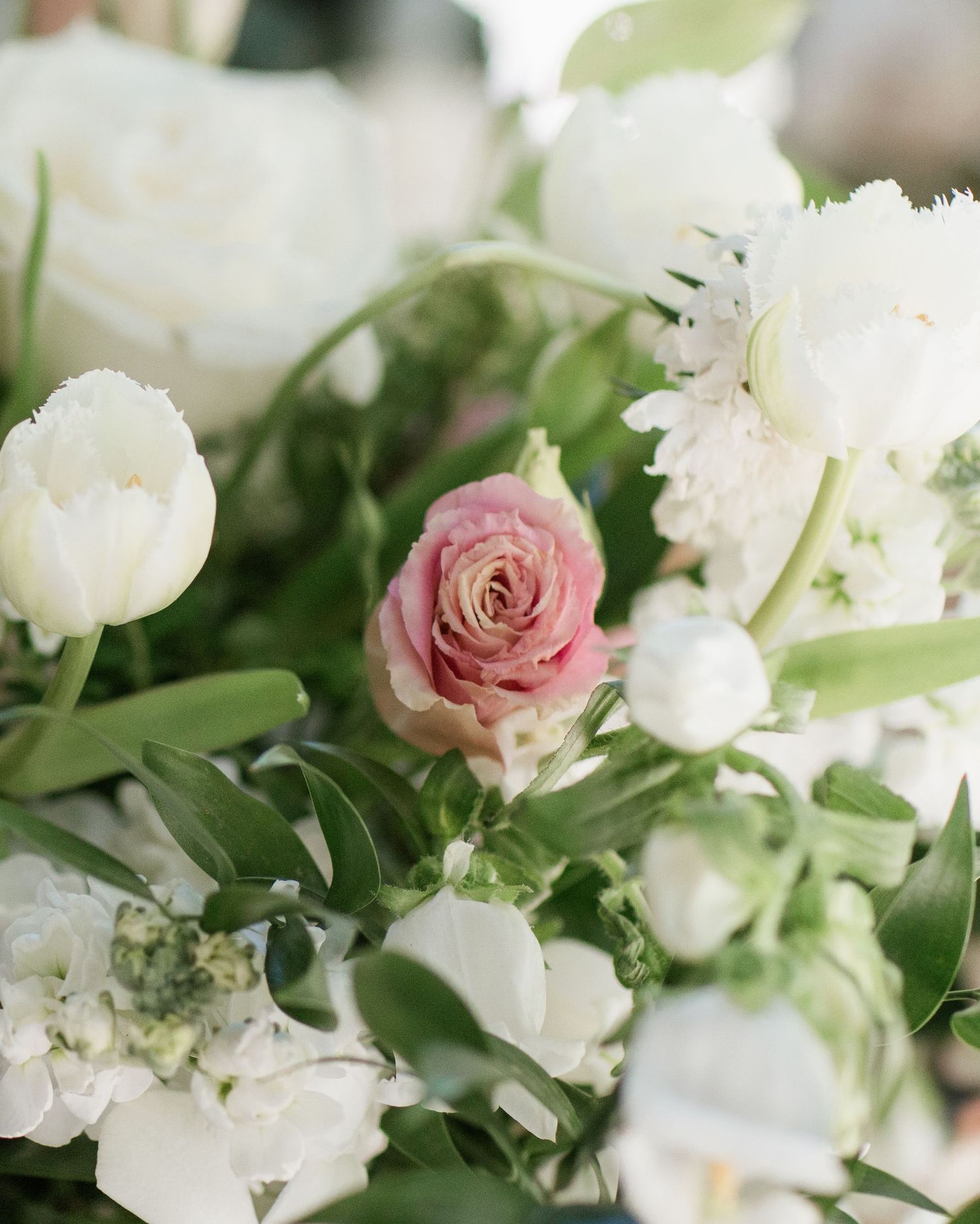 Fresh white and pink roses with greenery in romantic wedding bouquet arrangement.