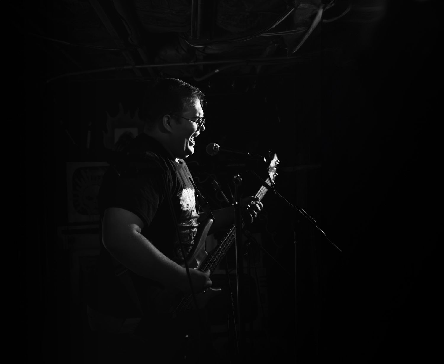 A dramatic black and white photo of a musician performing with a guitar in low-key lighting.