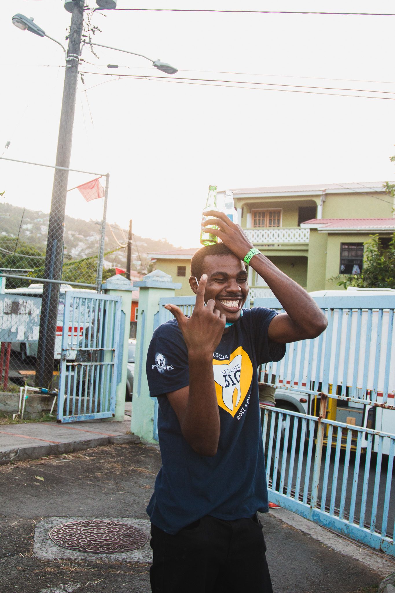 Energetic person in navy shirt dancing outdoors against blue fence.