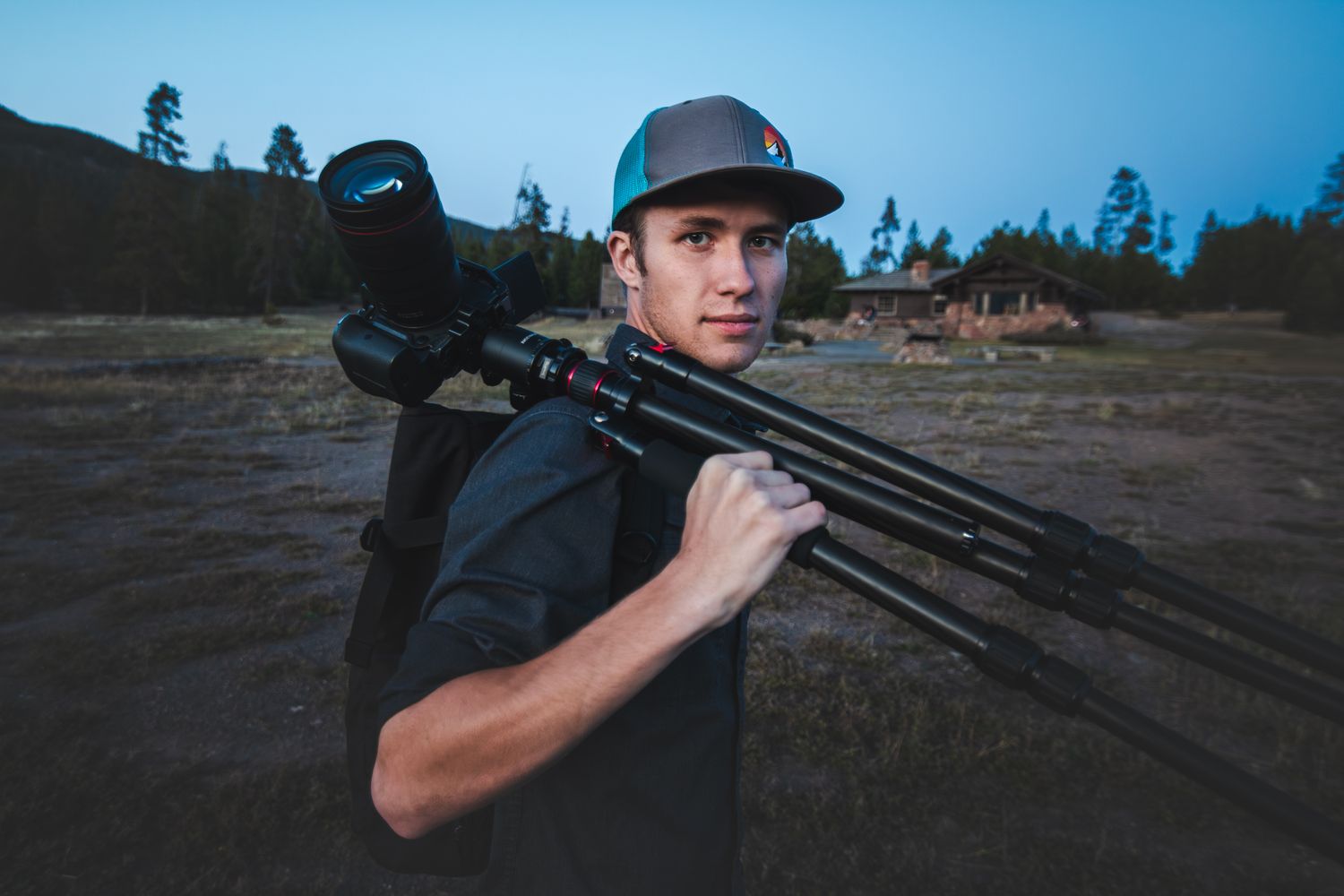 Person shooting a rifle outdoors against blue sky at dusk.