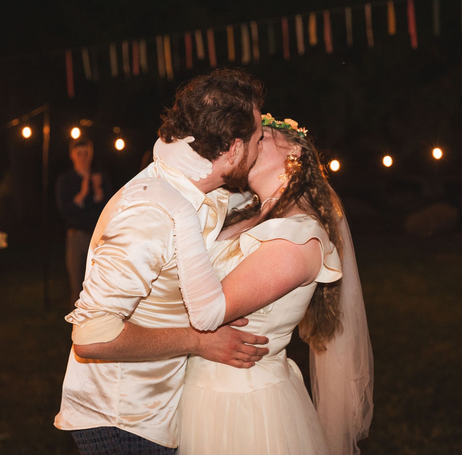 Romantic dance sequence at an evening wedding reception with string lights overhead.