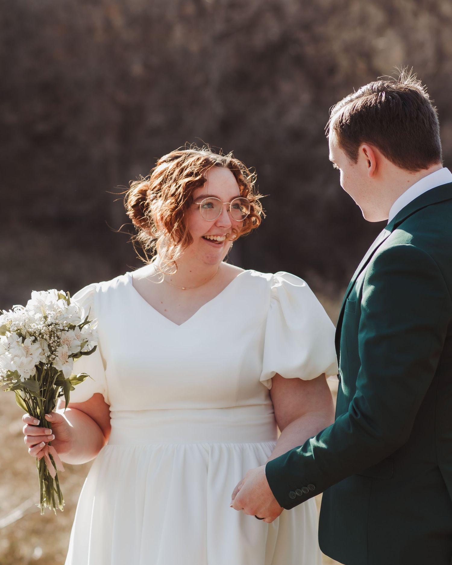Wedding scene with bride in white dress holding bouquet during outdoor ceremony.