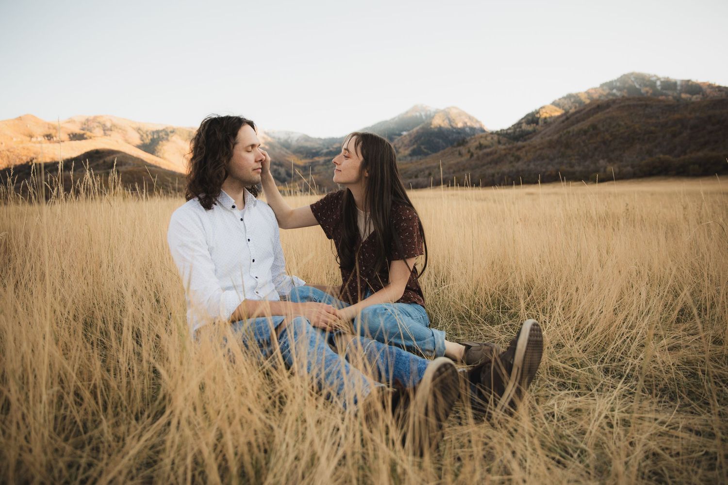 A couple dances together in a golden wheat field during sunset, creating a romantic silhouette against the warm sky.