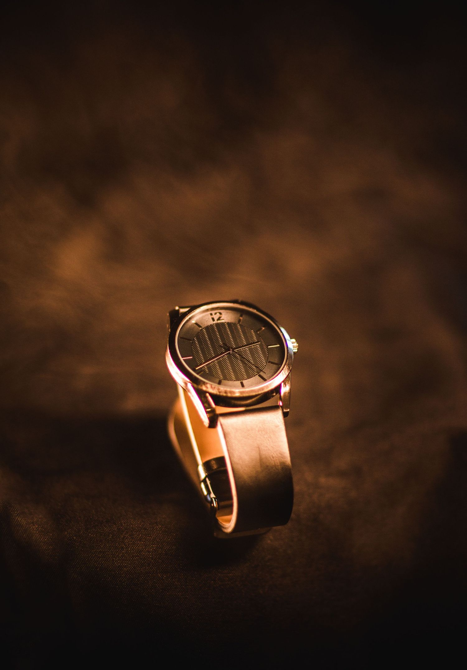 Classic wristwatch with leather band photographed on dark textured background.