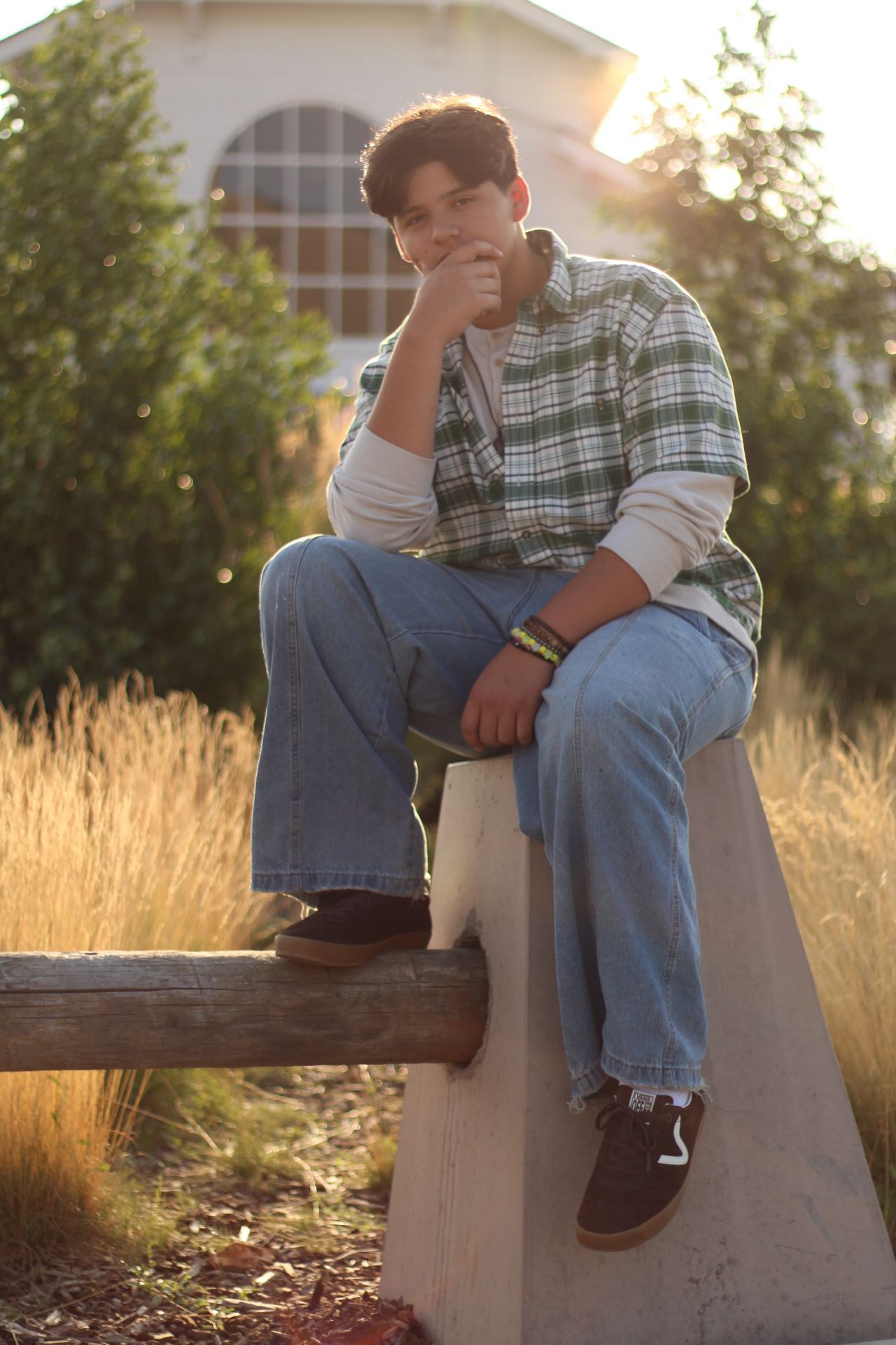Senior portrait of a young man sitting on a concrete barrier at sunset at the Missoula County fairgrounds.