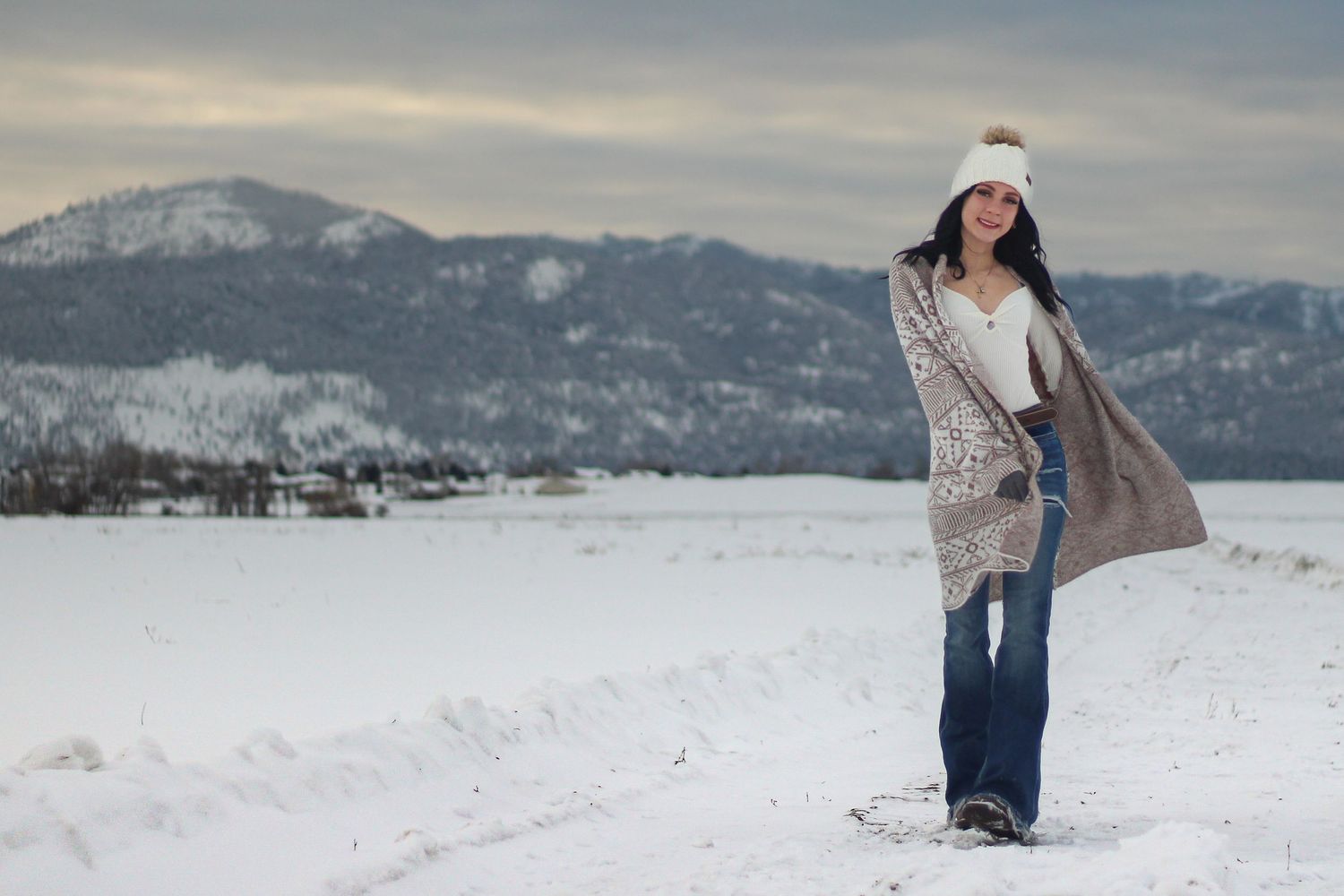 Senior portrait of young woman walking in the snow in Missoula, Mt with snowcapped mountains in the background.