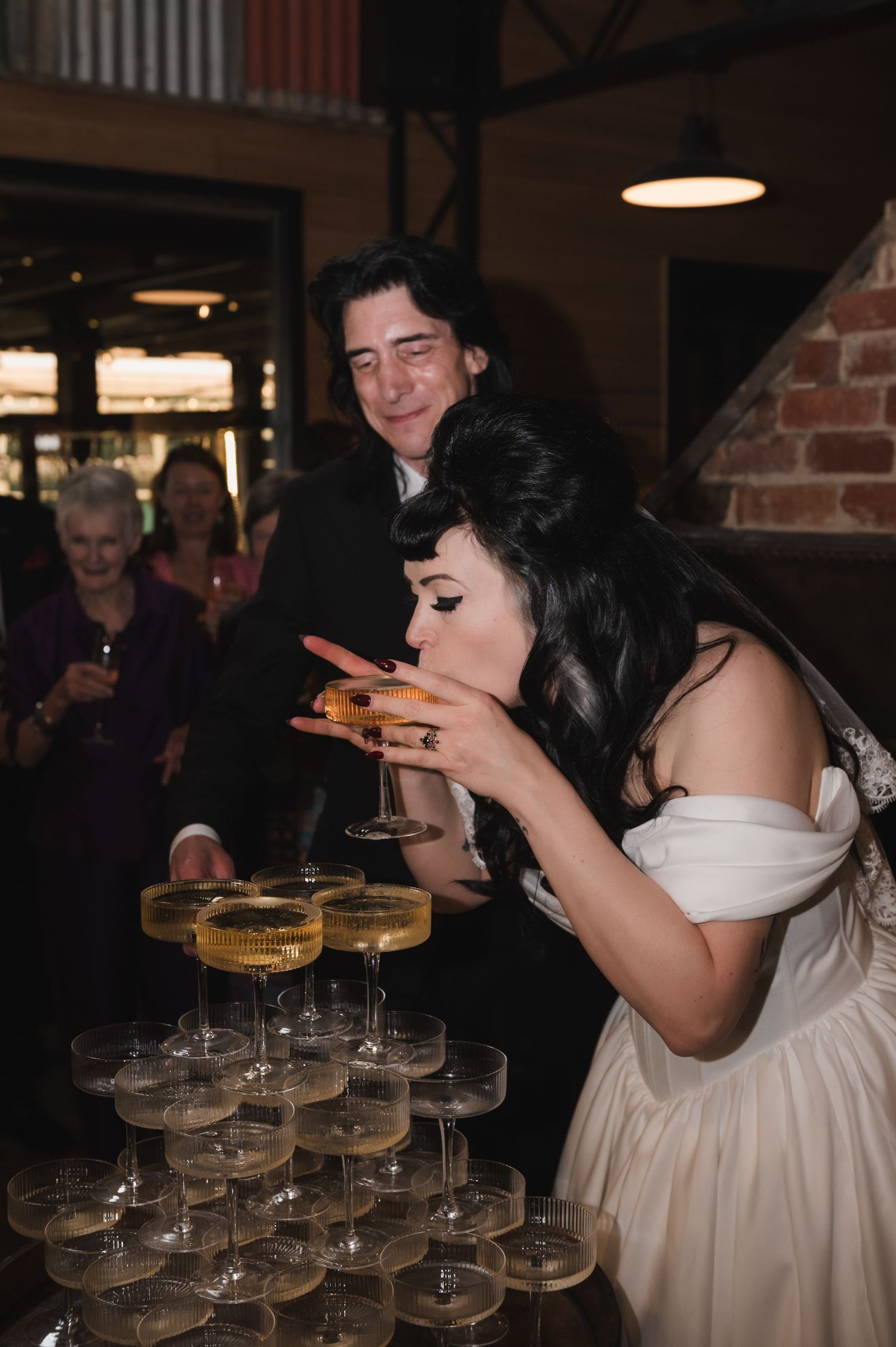 Wedding reception featuring a champagne tower with coupe glasses stacked in layers.