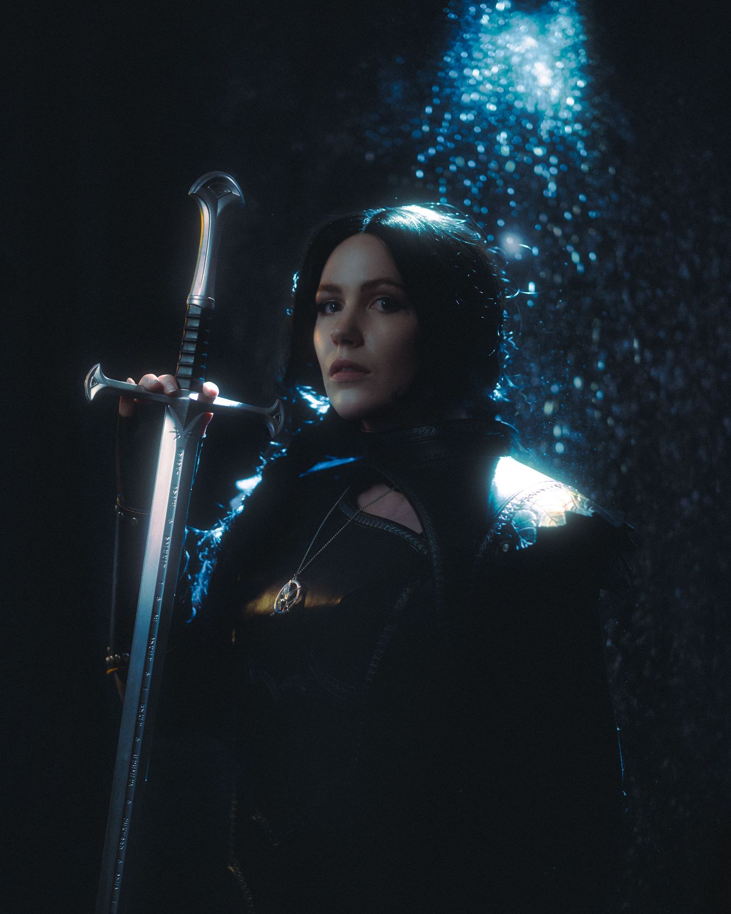 A dark fantasy portrait with a sword and glowing blue particles against a black background.