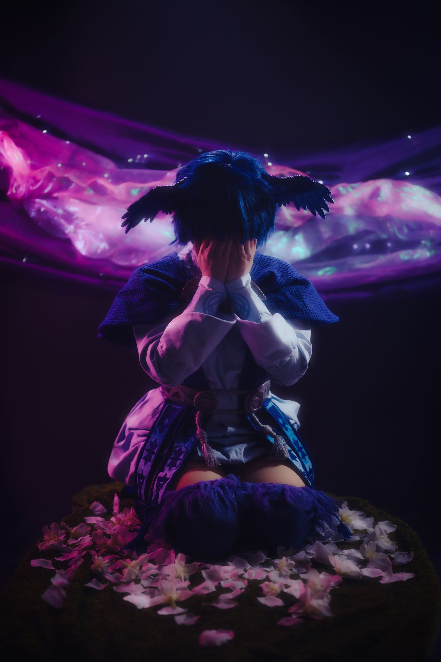 Ethereal scene with flowing fabric and feathers under purple and blue lighting.