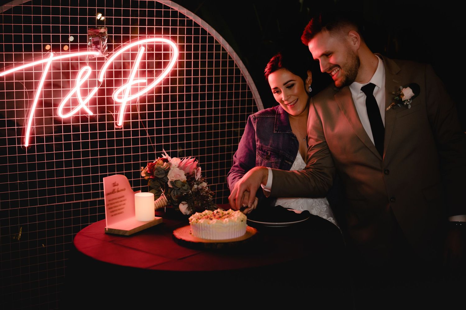 Red neon lights illuminate celebration scene with cake.