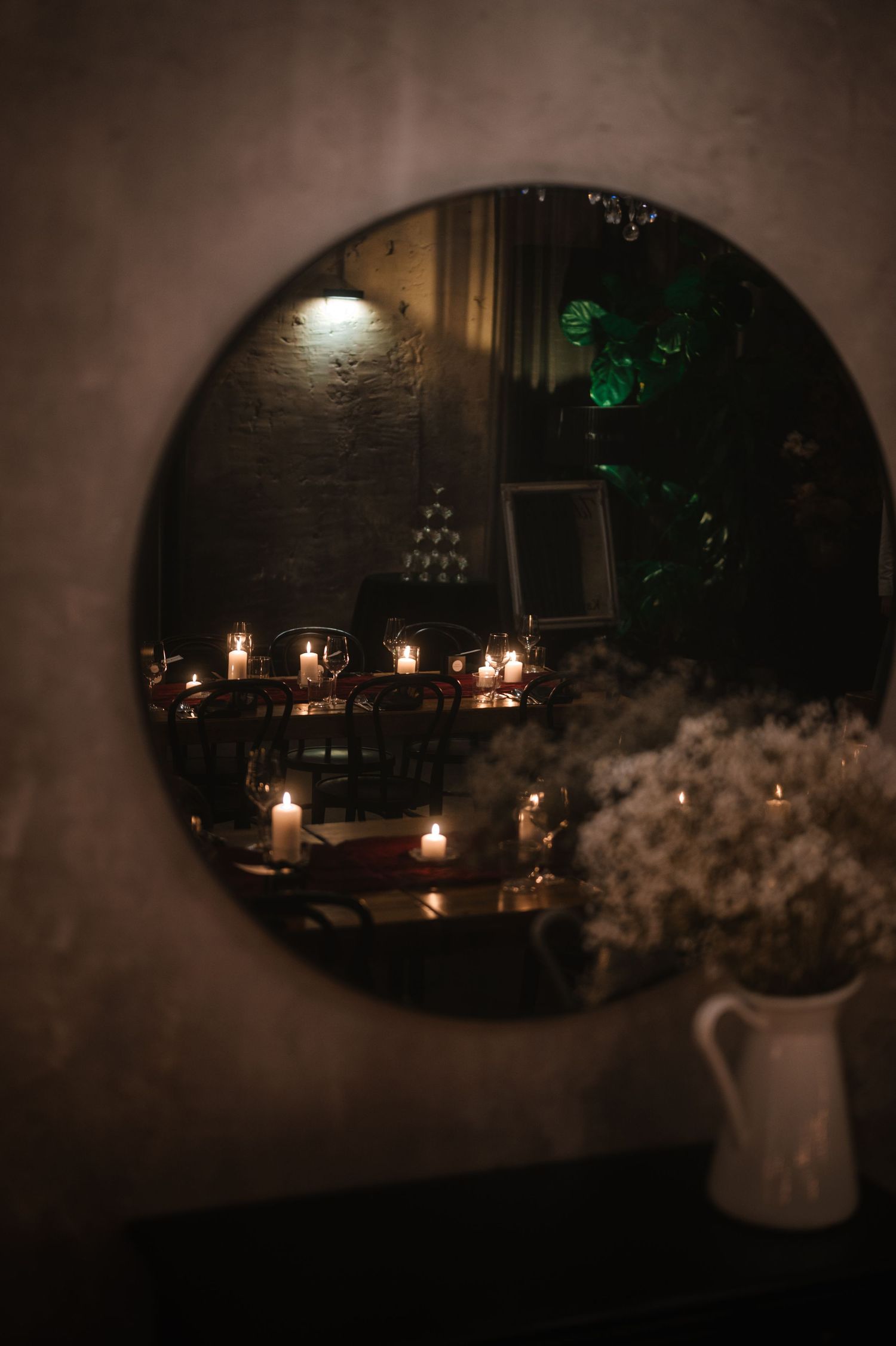 Candlelit table settings create an intimate ambiance in a dimly lit room.
