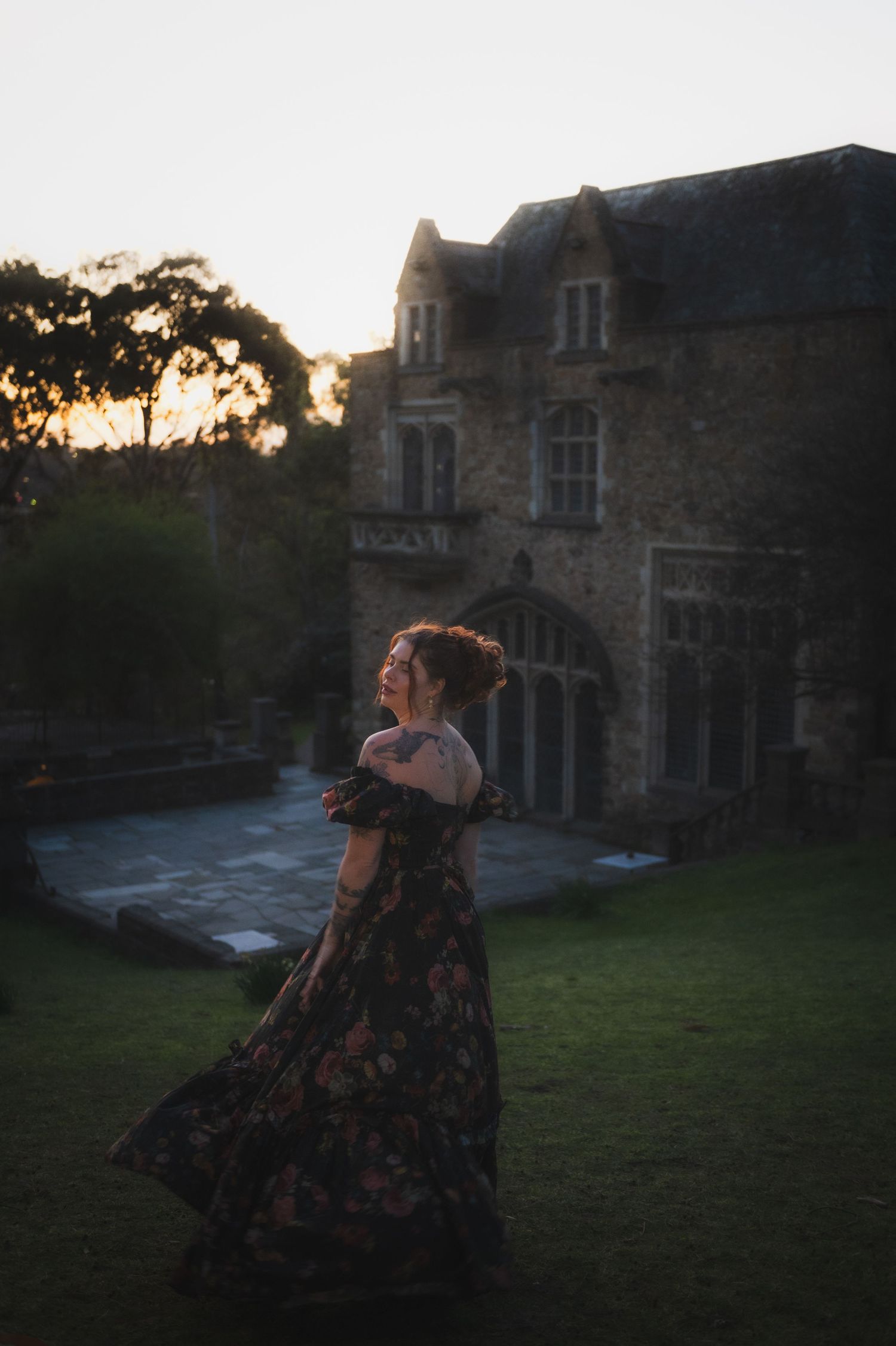 Silhouette of someone in a dress against a historic stone building at sunset.