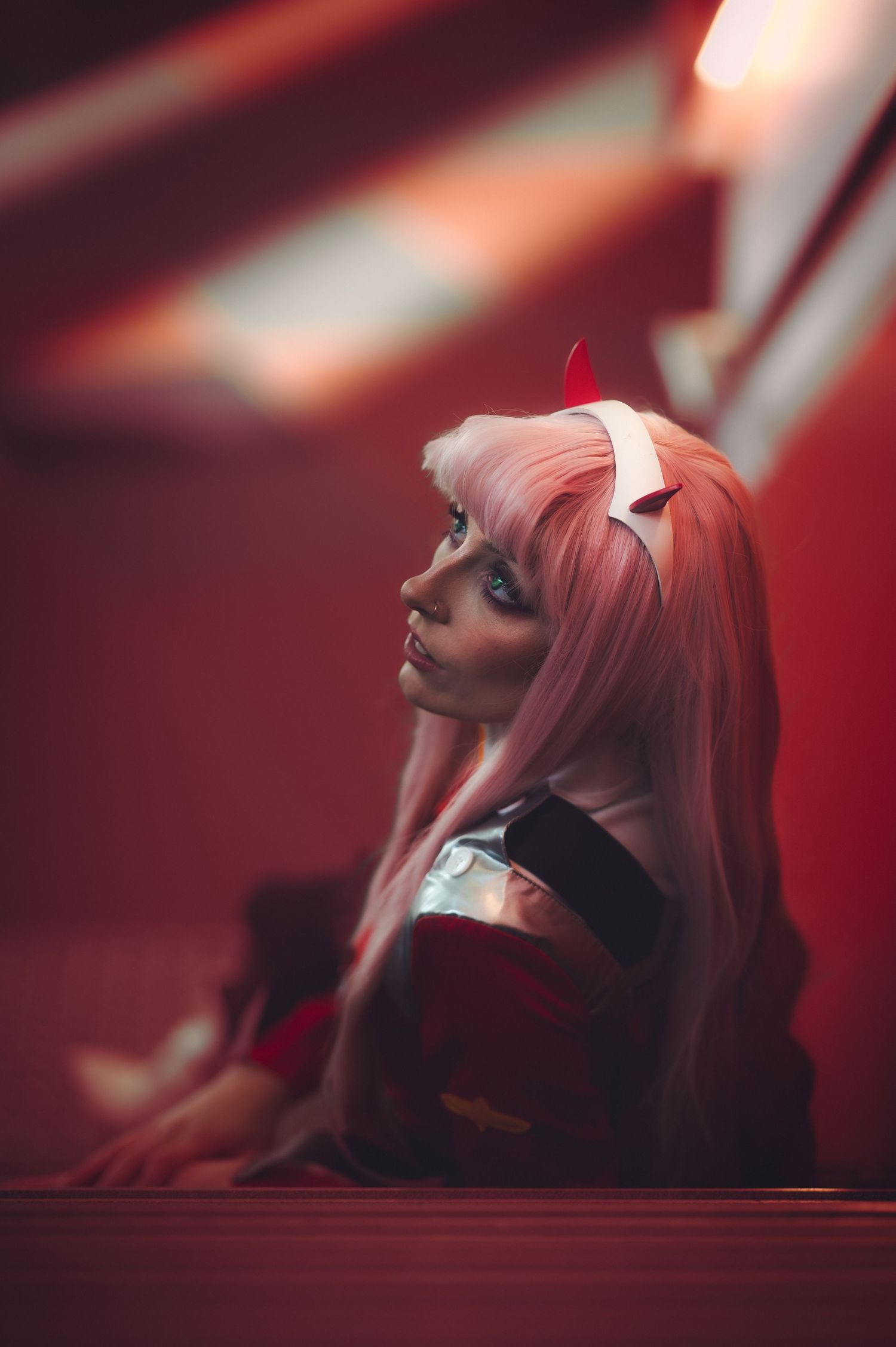 Pink-haired figure in artistic portrait with dramatic red lighting.