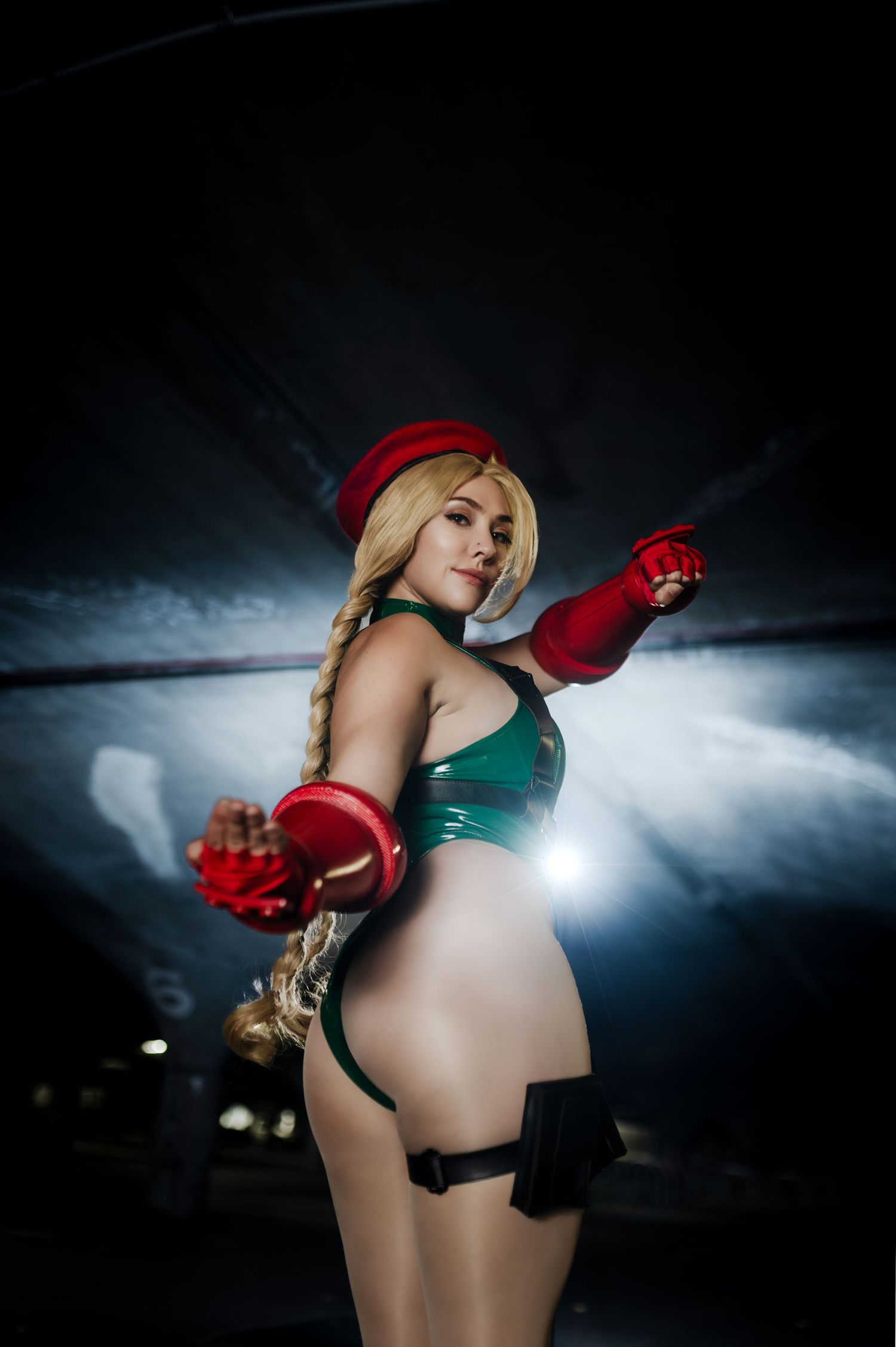 Cosplay portrait with green and red costume elements against dark background.