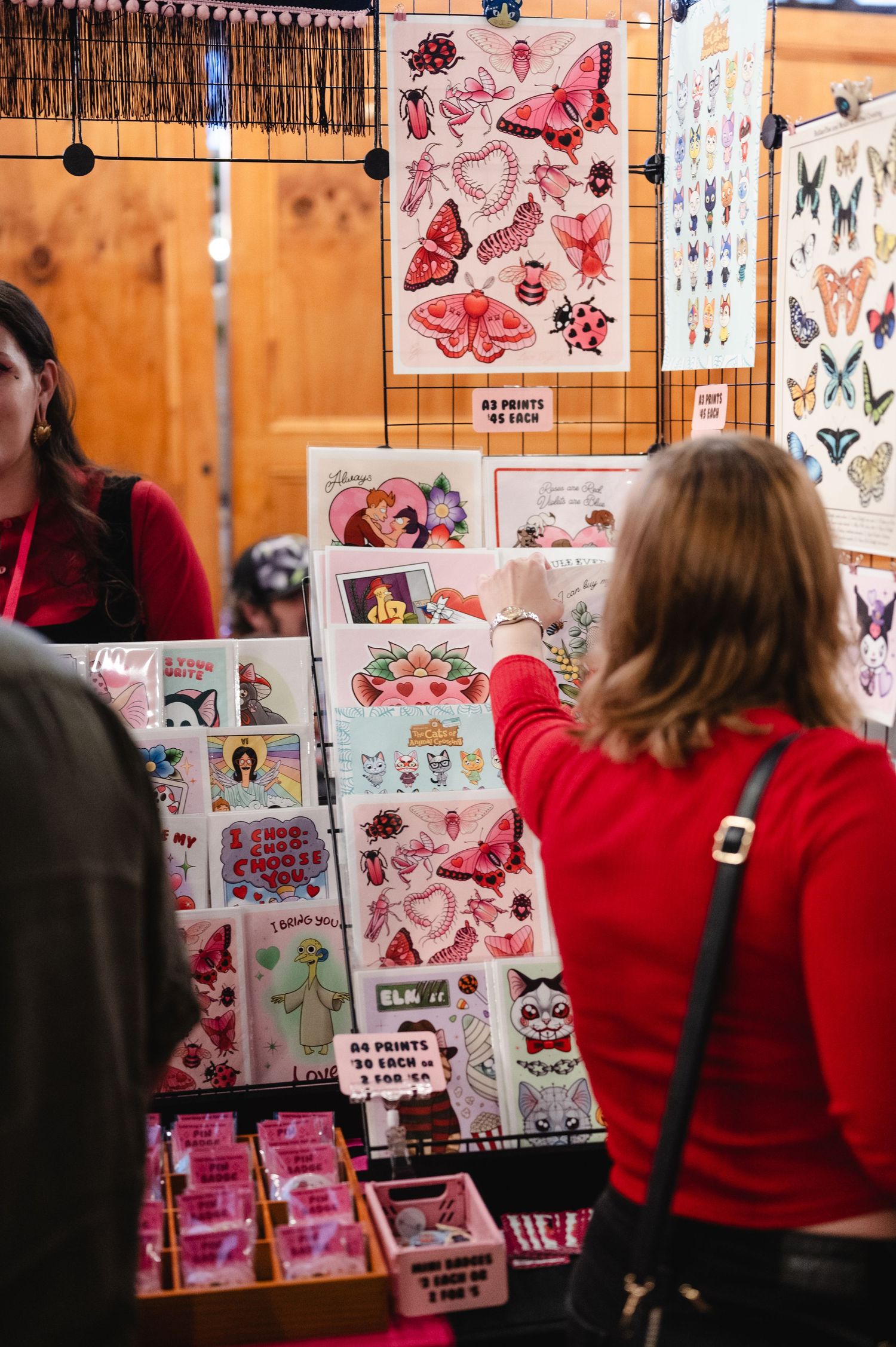 Vendor booth displaying colorful butterfly and floral artwork prints at a craft fair or art market.