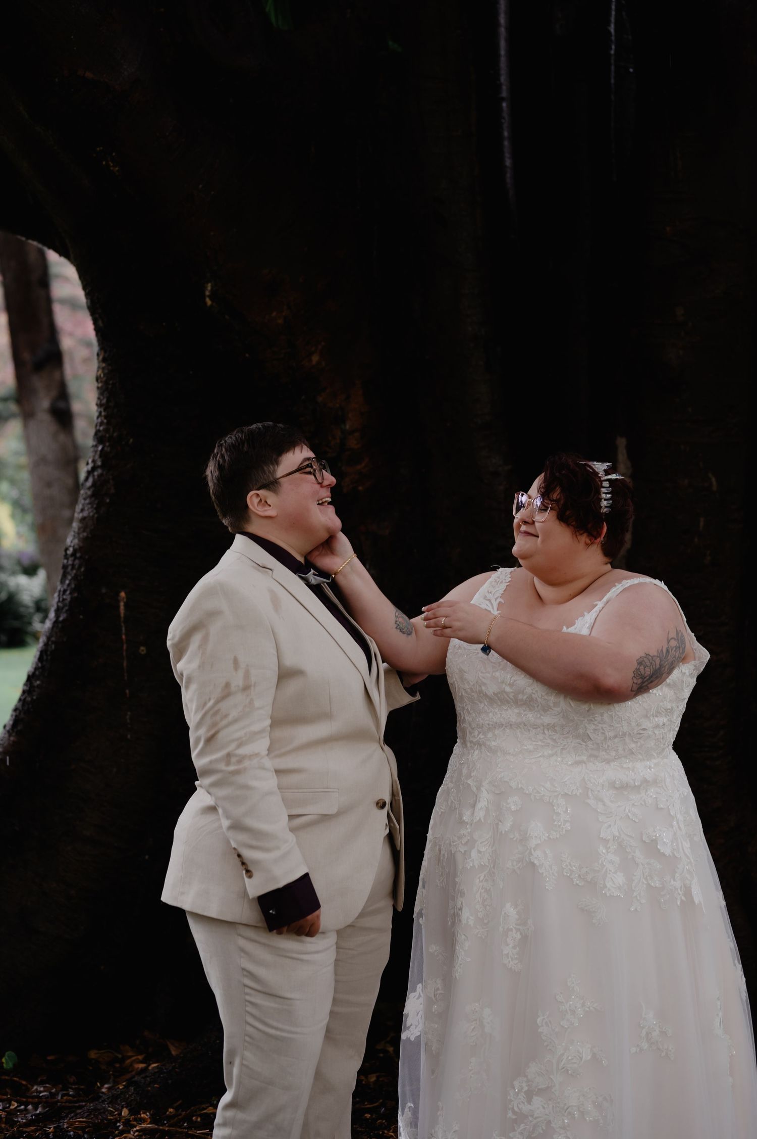 Wedding couple in white attire sharing tender moments outdoors during their ceremony.