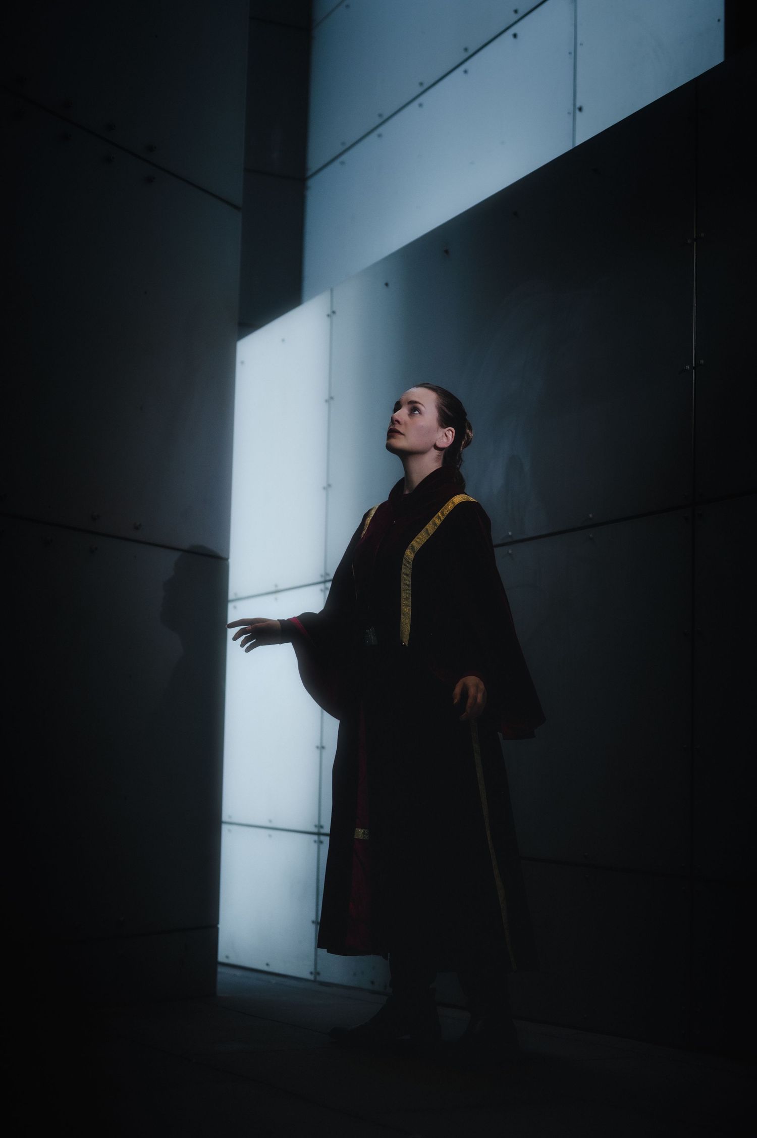 Moody silhouette portrait in dark corridor with dramatic side lighting.