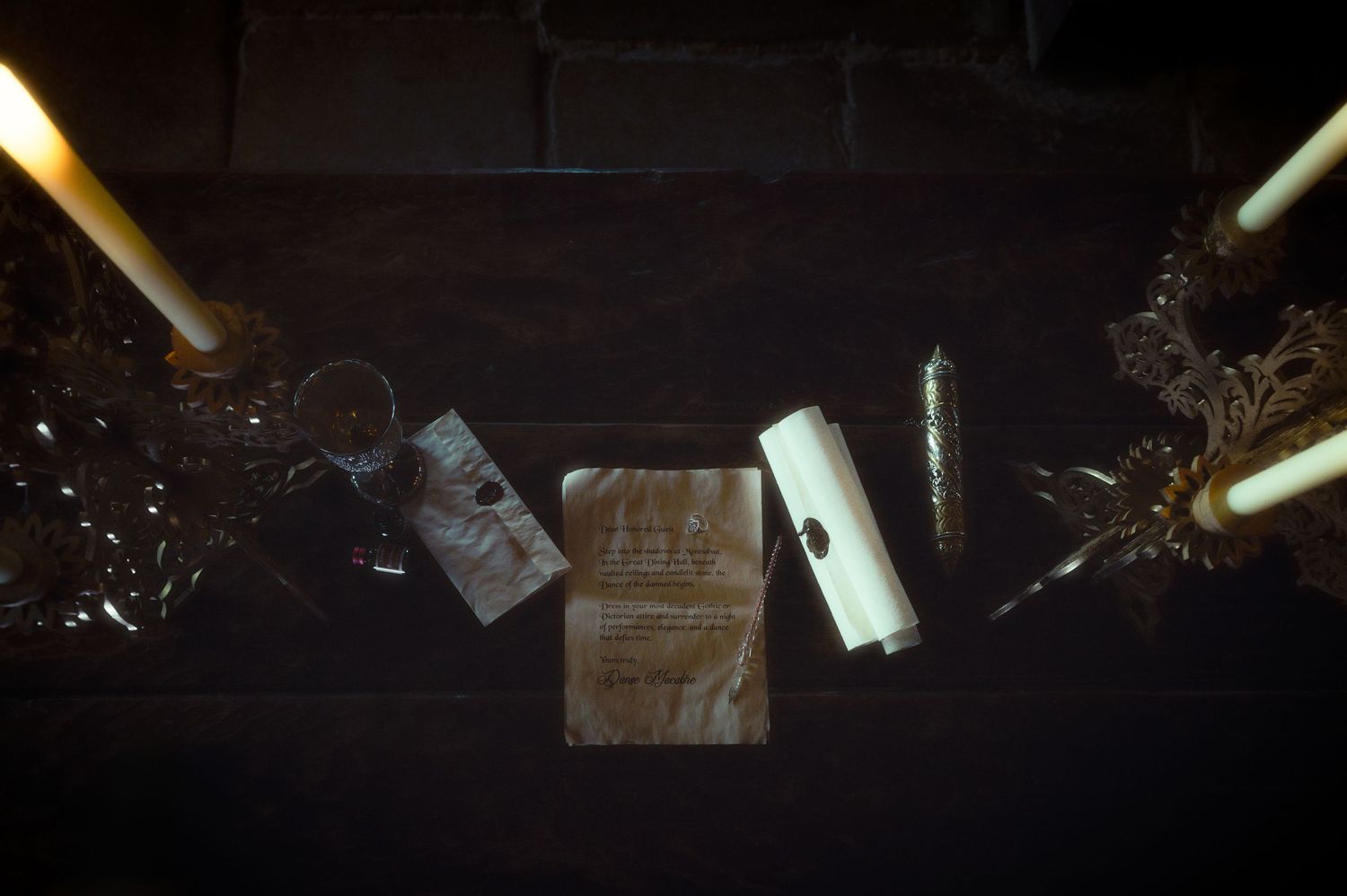 Aerial view of candles, scrolls, and ornate decorations arranged on a dark wooden surface in dim lighting.