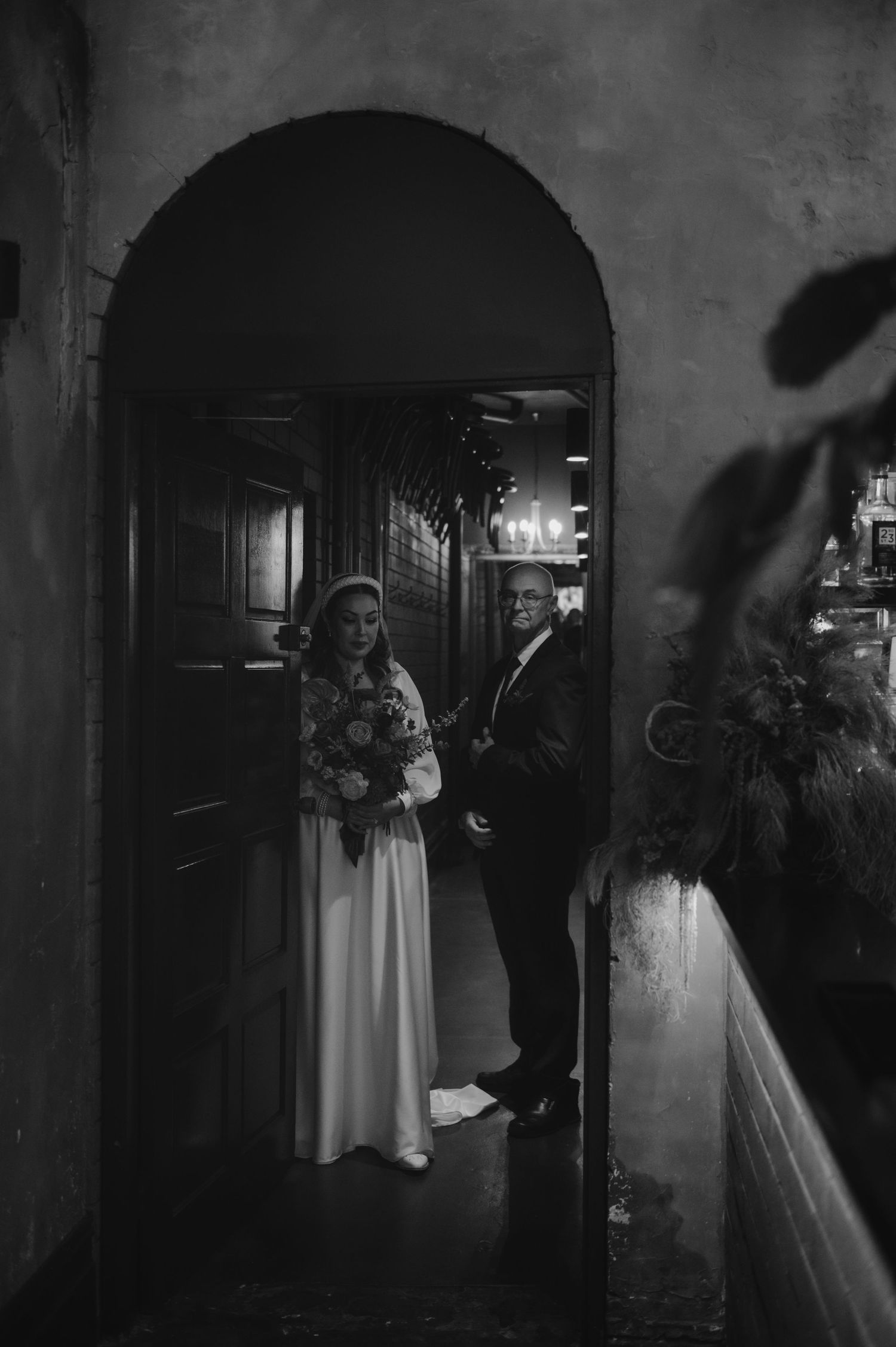 A series of black and white wedding photos showing a couple in a dimly lit hallway with arched doorways.