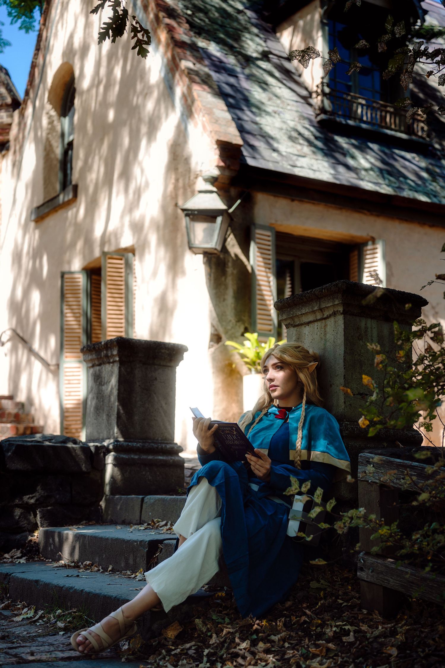 Peaceful cosplay scene of someone reading on stone steps of a historic building.