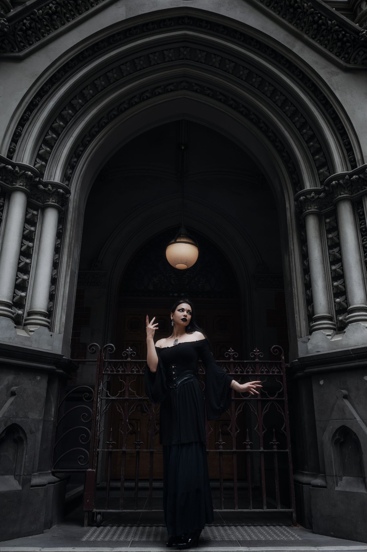 Gothic architectural doorway framing a dramatic dark fashion scene.