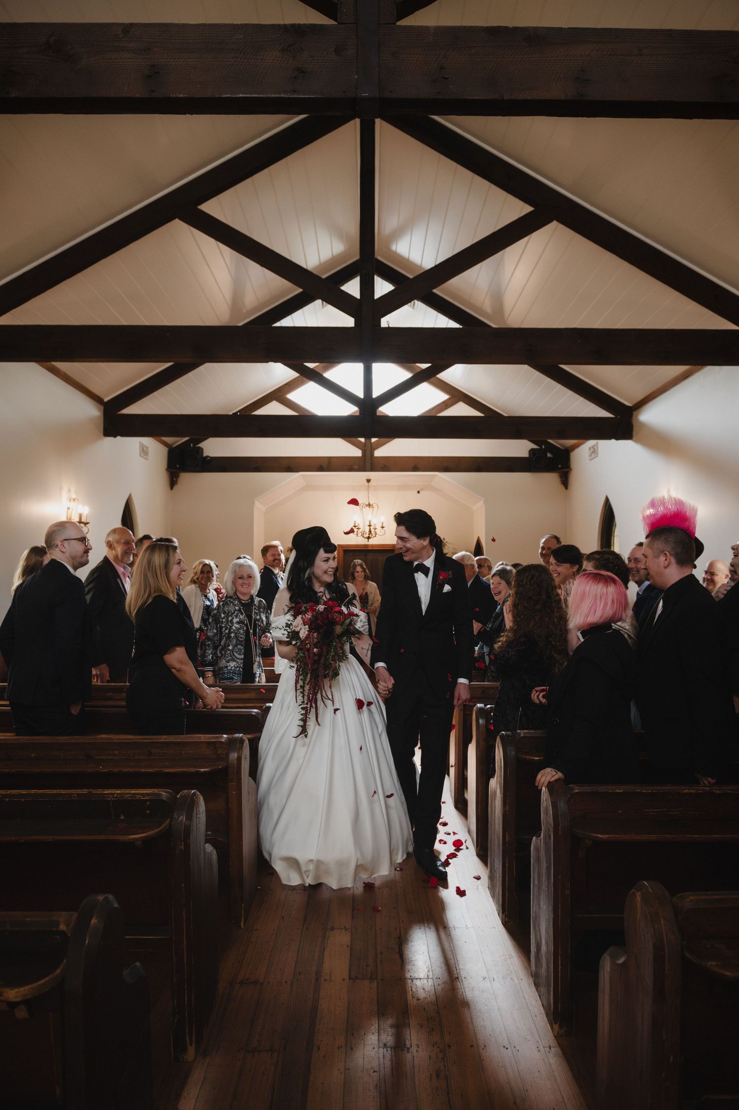Bride and groom walking down church aisle after wedding ceremony surrounded by guests.