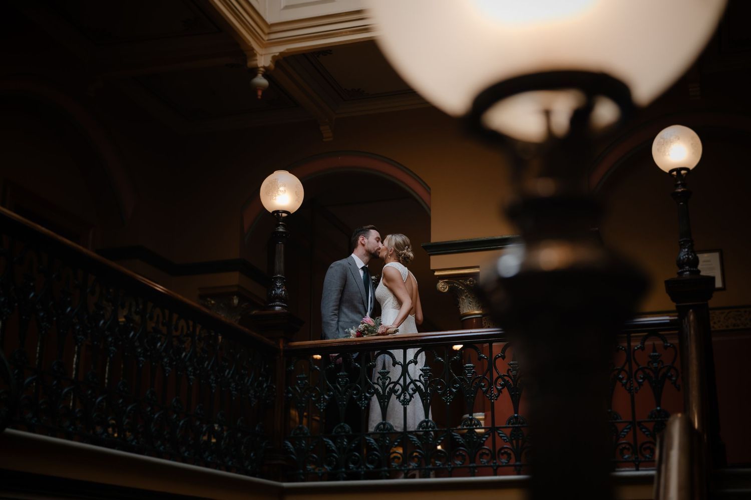 Silhouetted figures on an elegant balcony beneath vintage pendant lights.