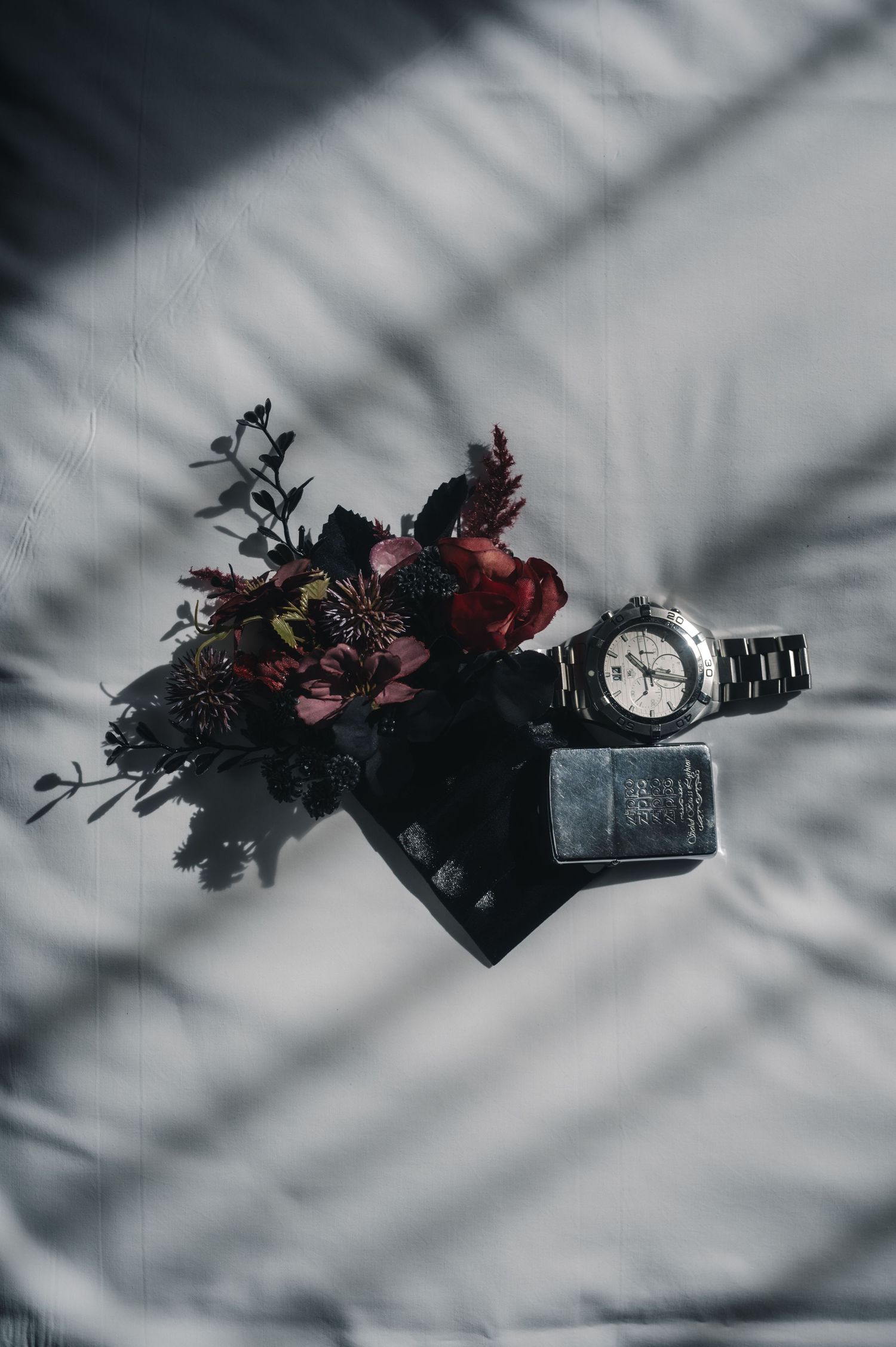 Dark moody floral arrangement with shadows cast on white surface.