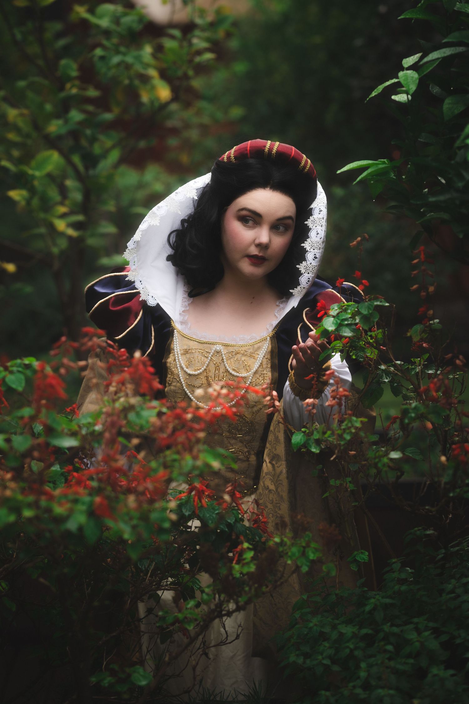 Medieval fantasy costume portrait among red flowers and green foliage.
