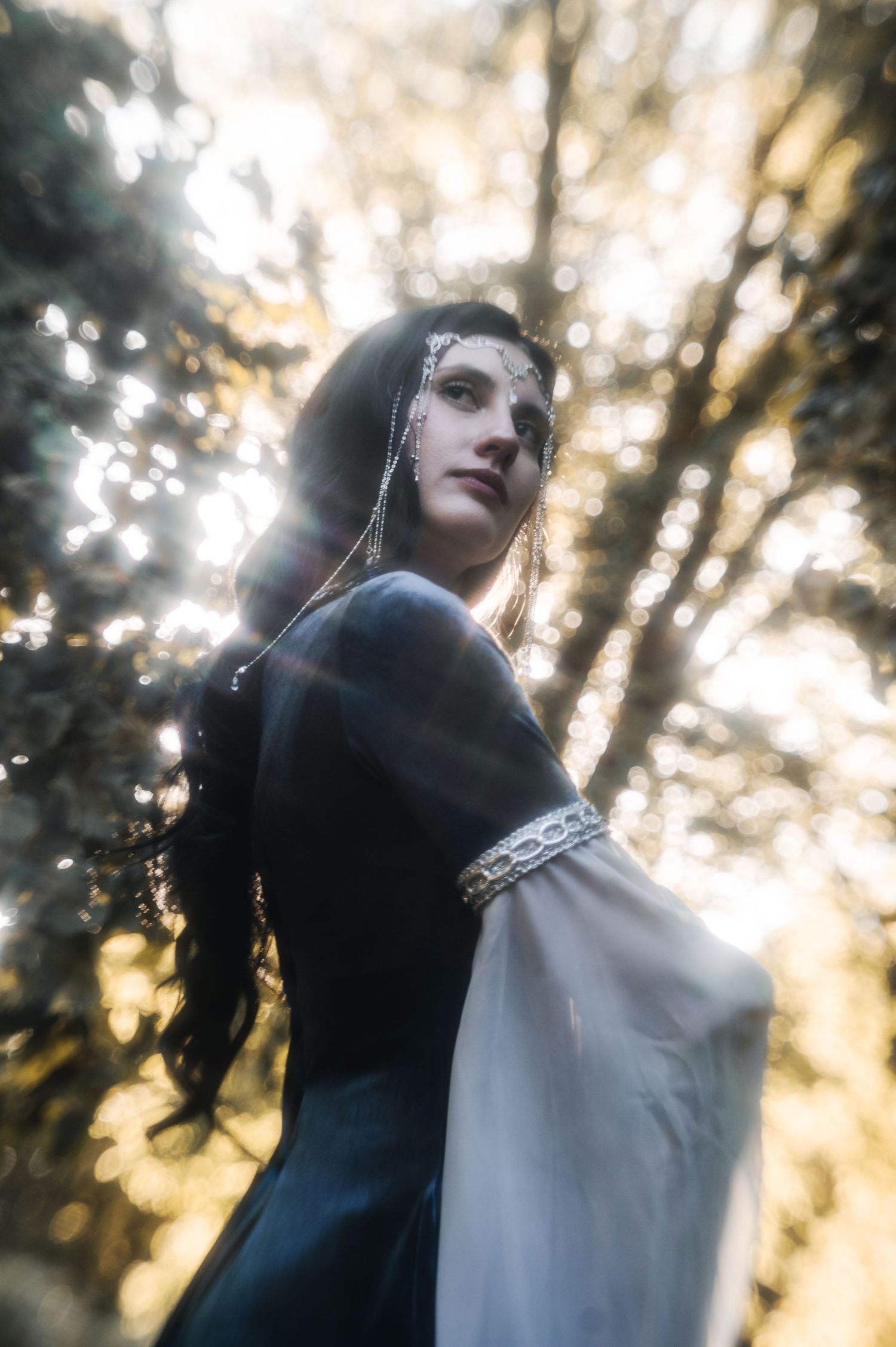 Ethereal medieval-style portrait in a forest with sunlight streaming through trees.