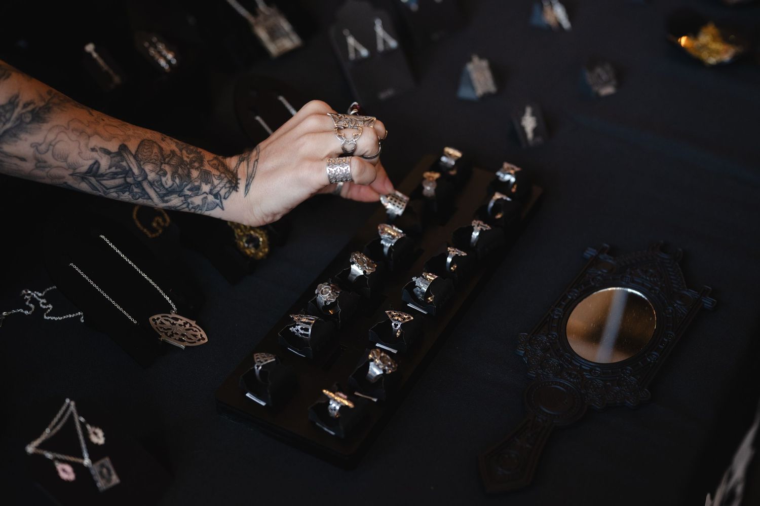 A person's hand pours liquor from a bottle into a cocktail mixing glass on a dark wooden bar counter.