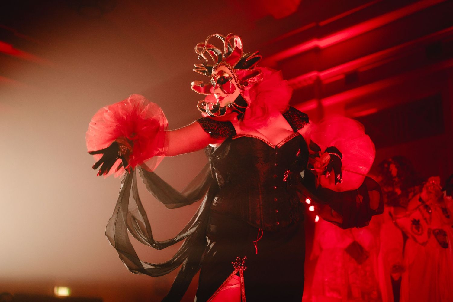 Concert performers on stage bathed in dramatic red lighting during a live music performance.