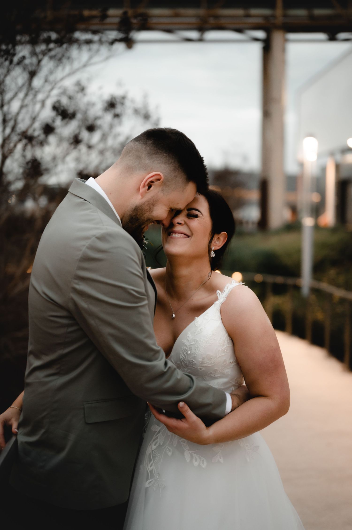 Couple embraces during sunset photoshoot with warm lighting.