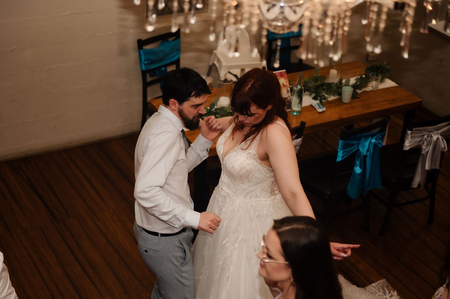 Wedding party dancing and celebrating during a reception under elegant chandeliers.