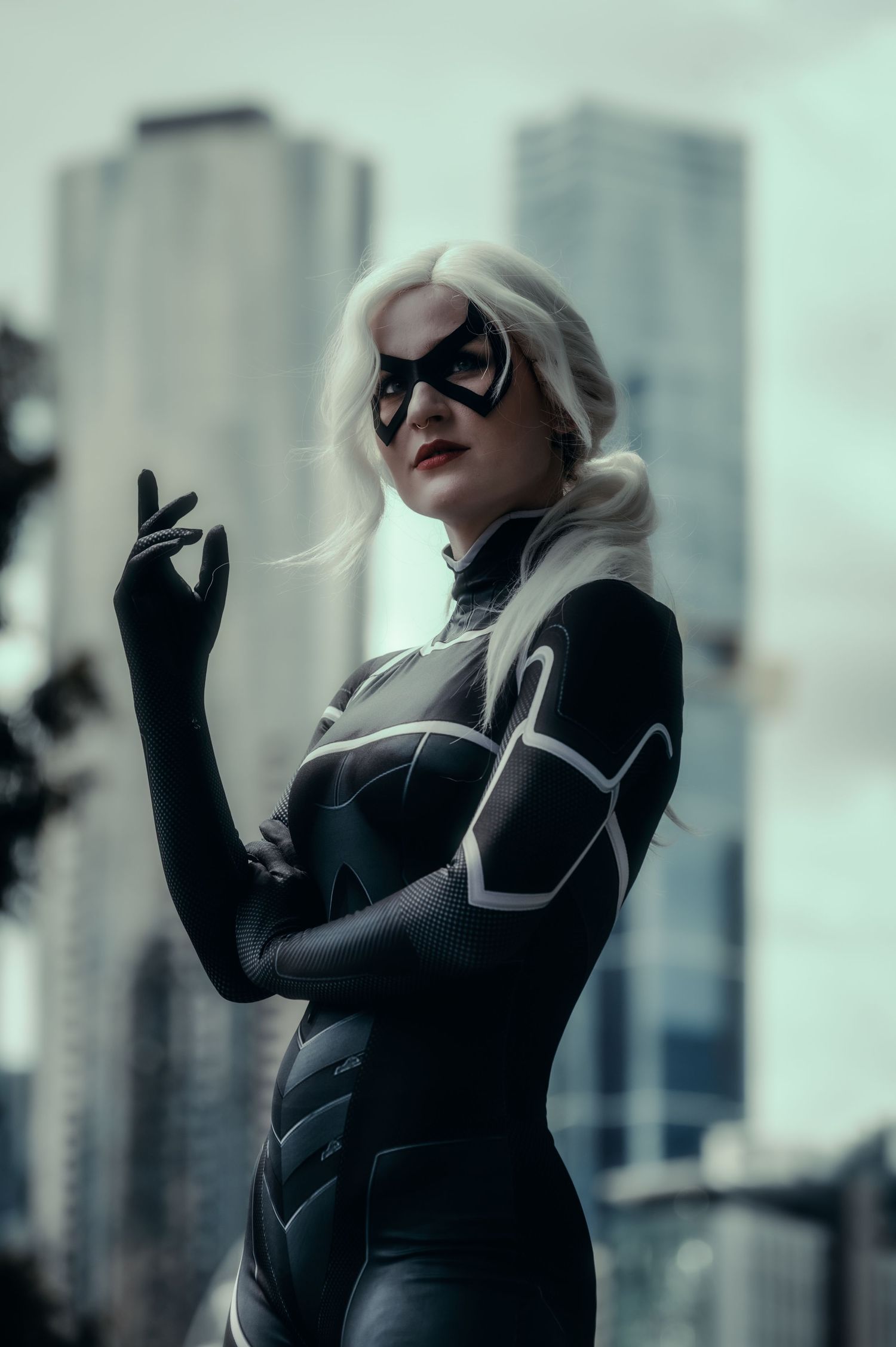 Figure in black attire strikes dramatic poses against an urban cityscape backdrop.