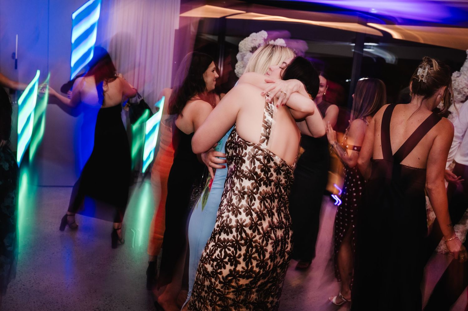Wedding reception dance floor lit with colorful blue and green lights.