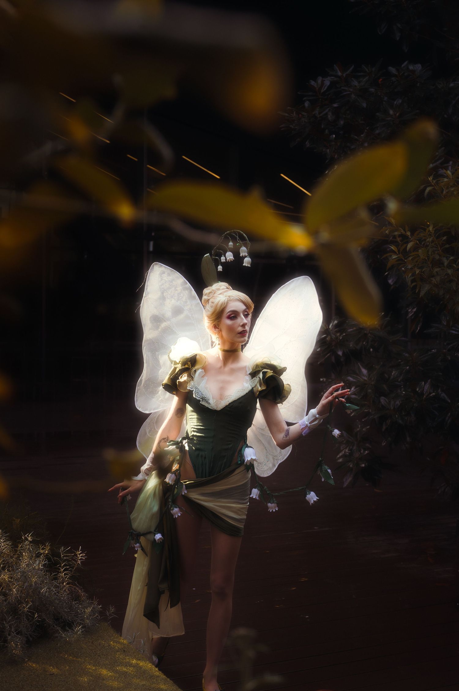 Ethereal fairy figure with glowing wings dancing among dark foliage.