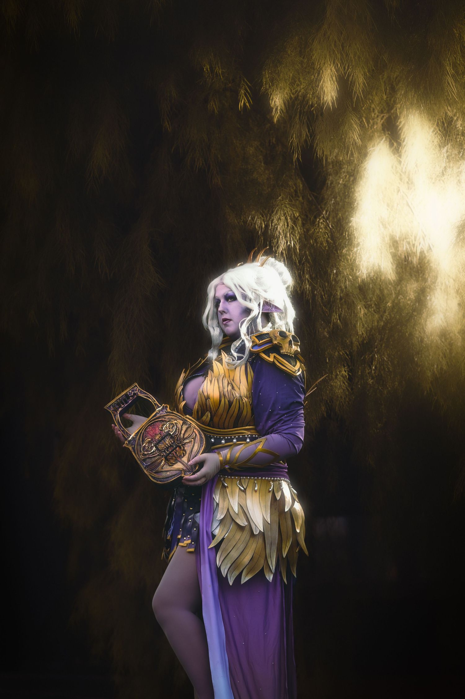 Fantasy warrior cosplay with gold and purple armor against dark background.