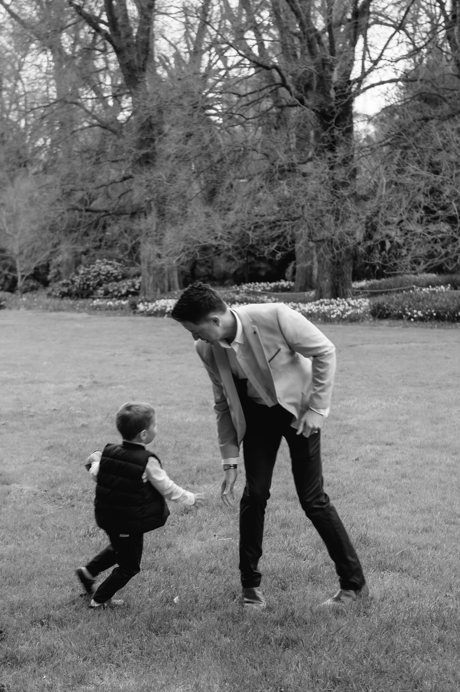 A touching black and white moment between parent and child playing on a grassy lawn.