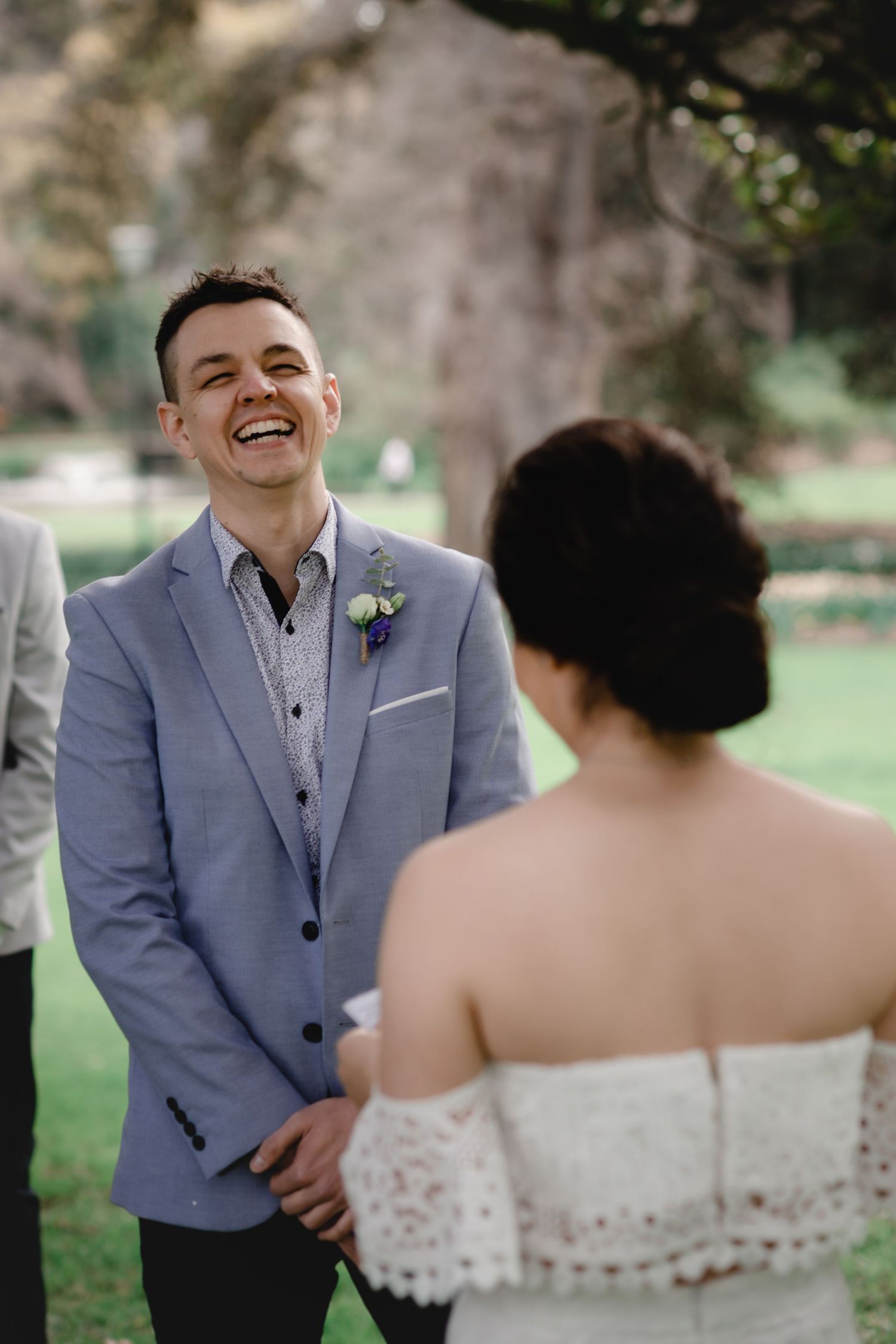 A joyful moment during outdoor wedding portraits in a garden setting.