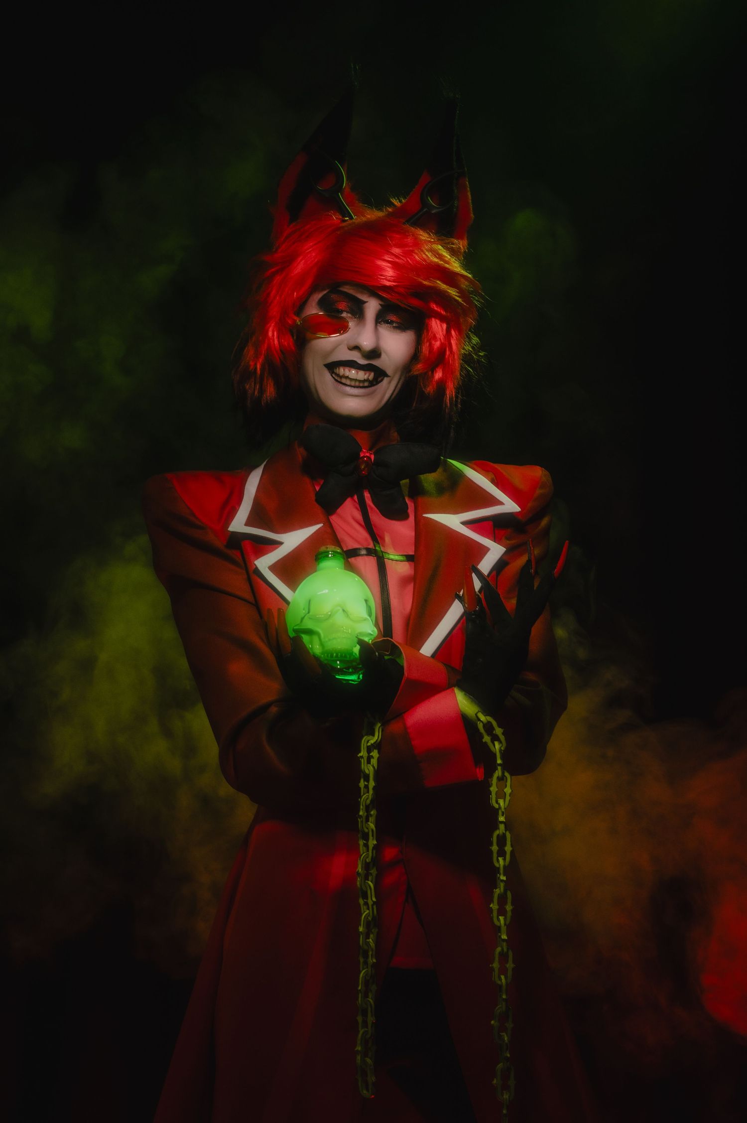 Theatrical performer in red costume with glowing green accents in dark atmospheric setting.