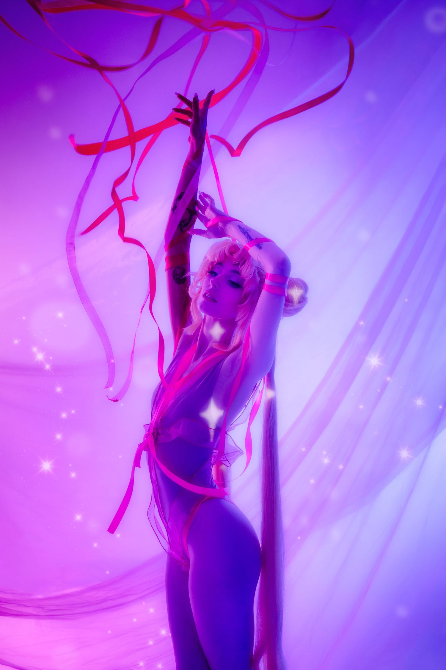 A dancer poses gracefully under purple neon lights with flowing red ribbons against a dreamy glowing backdrop.