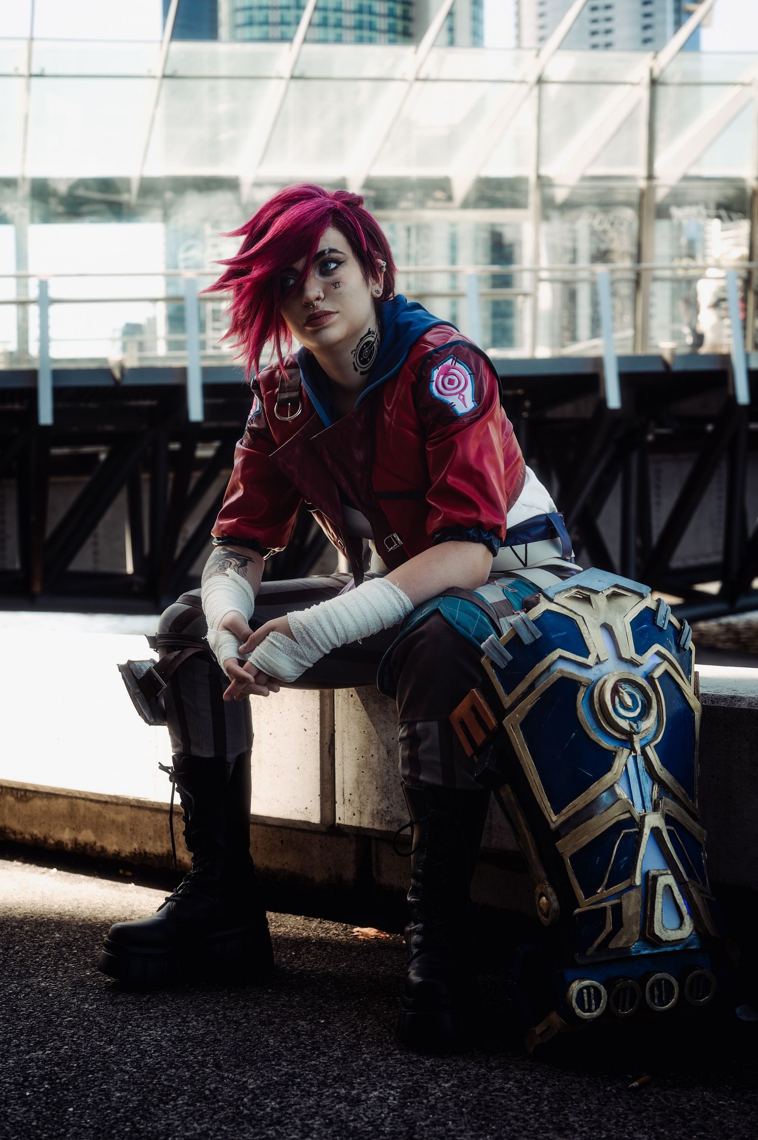 Cosplayer in detailed costume rests against industrial background.