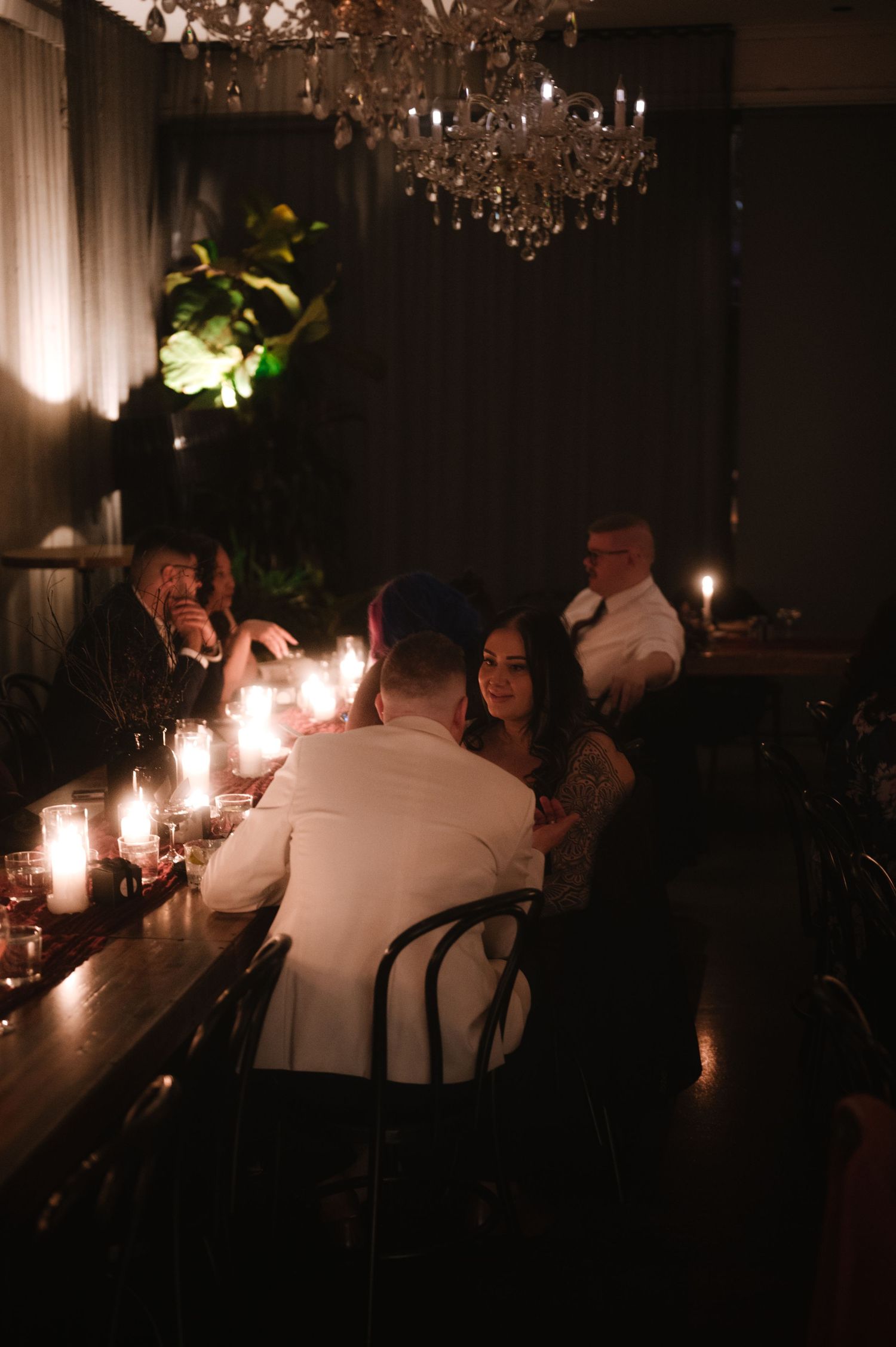 Candlelit reception tables with crystal chandeliers create an intimate wedding atmosphere.