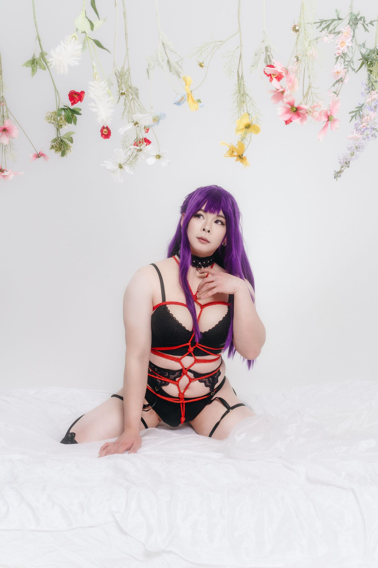 Glamour portrait session with hanging floral decorations and dramatic purple hair styling.