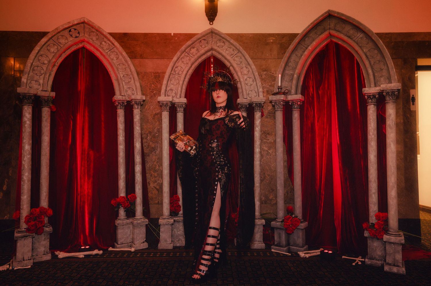 Gothic stone arches and red velvet curtains create a dramatic medieval atmosphere in a dimly lit hallway.