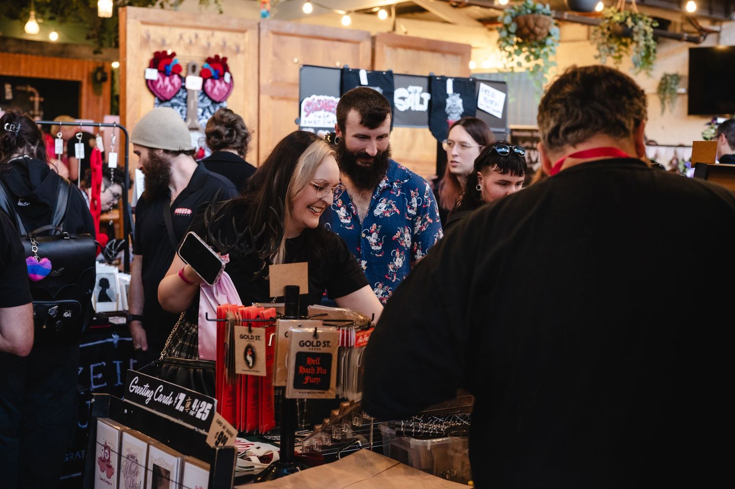 A bustling indoor market space with vendor stalls and shoppers browsing local goods and merchandise.