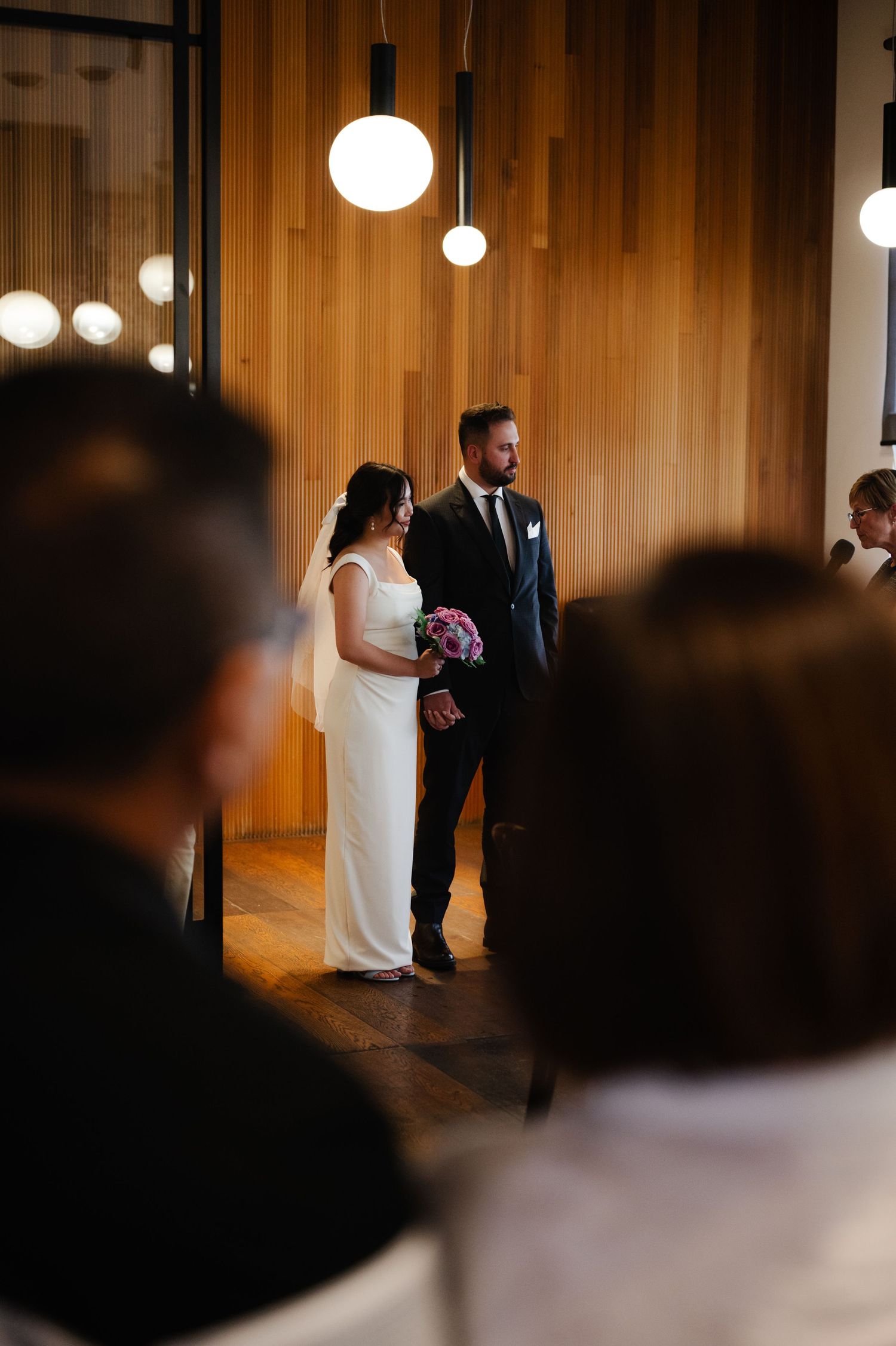 Wedding ceremony in a modern wooden venue with pendant lighting.