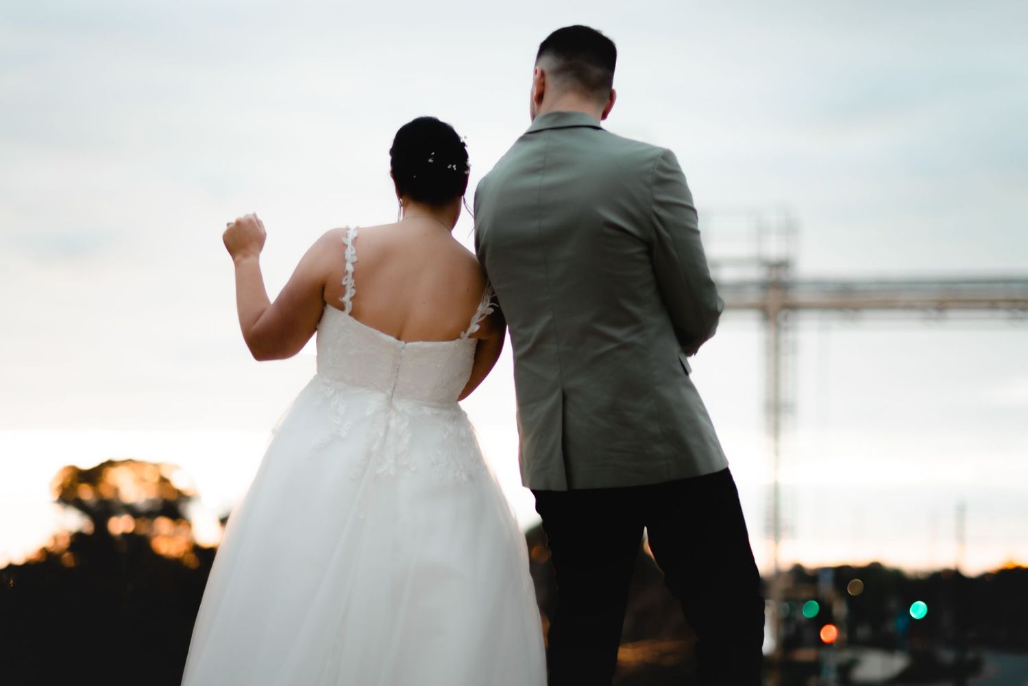 Couple walks together at sunset against urban backdrop.
